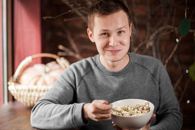 Portrait of smiling man sitting with bowl at table