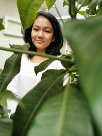 Portrait of a smiling young girl behind the leaves