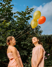 Portrait of a smiling girls with balloons against trees