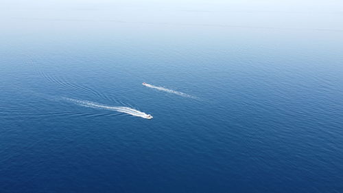 Two boats cross each other on glassy water in the south of thassos in the greek aegean sea.