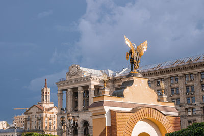 Gold plated bronze statue of archangel michael in city square on sunny day