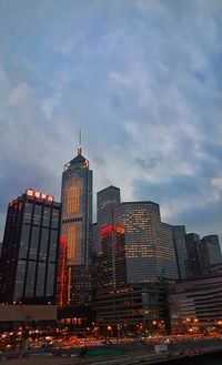 Illuminated buildings in city against cloudy sky