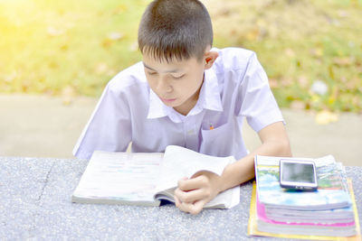 Boy reading book while studying at park