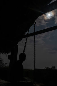 Low angle view of man sitting on swing against sky