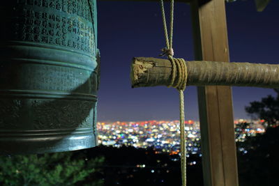 Close-up of wooden pole tied with rope by bell