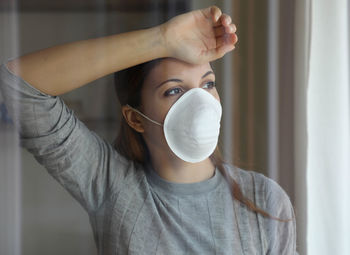 Young woman with mask looking away at home