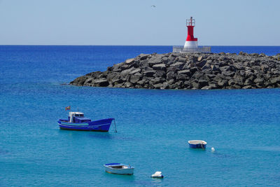 Lighthouse by sea against blue sky