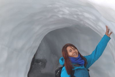 Portrait of a smiling young woman standing in snow