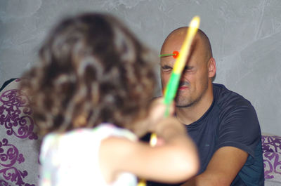 A baby archer shooting at her daddy with toy bow and arrows