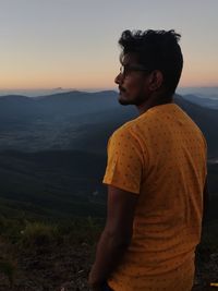 Young man looking away at sunset