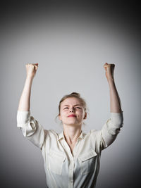 Portrait of young woman standing against gray background