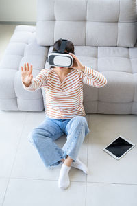 Young woman using digital tablet while sitting on sofa at home