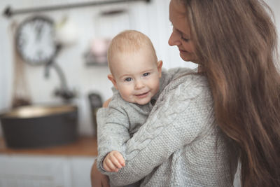 Mom and baby together in gray knitted sweaters in the real kitchen 