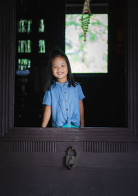 Portrait of smiling girl looking through window
