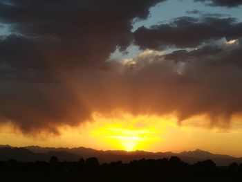 Silhouette landscape against dramatic sky during sunset