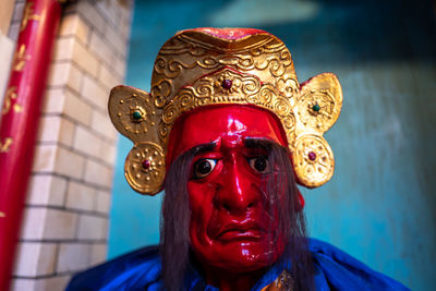 Close-up portrait of person wearing mask against wall