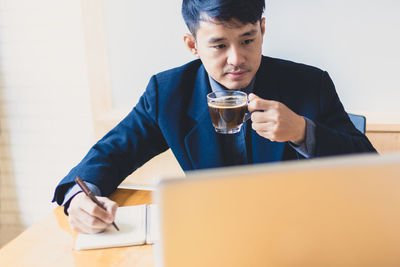 Mid adult man using mobile phone while sitting on table