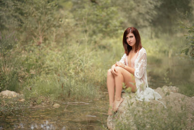 Portrait of beautiful woman sitting on rock
