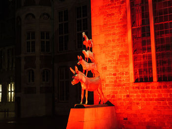 Statue against red wall and building