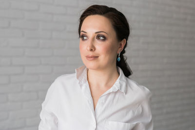 Portrait of young woman standing against wall