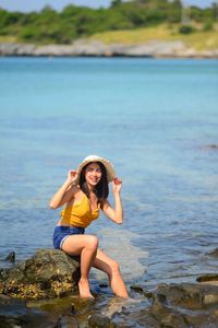 Portrait of woman smiling while standing on rock