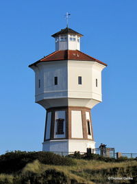 Low angle view of bell tower against clear blue sky