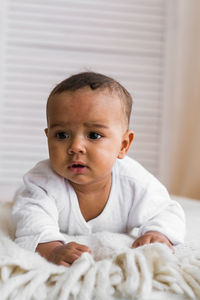 Portrait of cute baby on bed at home