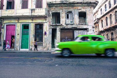 Green car on street against buildings