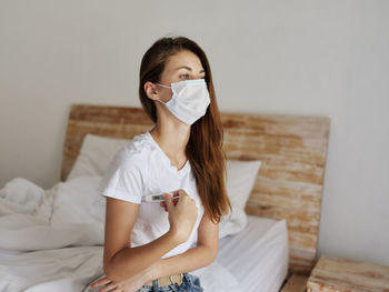 Young woman sitting on bed at home