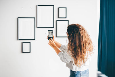 Young woman using mobile phone against white background