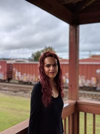 Portrait of smiling young woman standing on porch