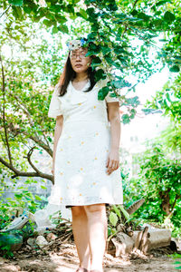 Portrait of young woman standing against tree