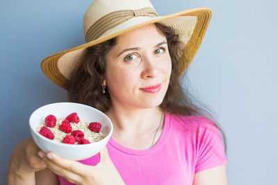 Portrait of woman holding ice cream against white background