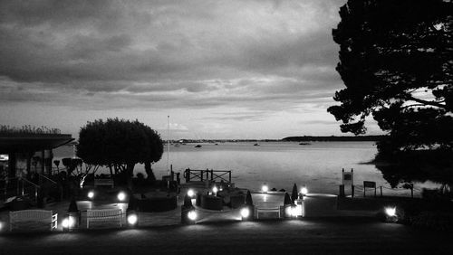 Illuminated table by sea against sky