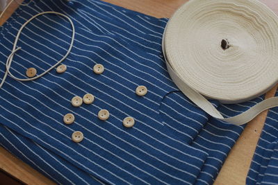 High angle view of blue cloth with sewing items on table