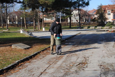 Rear view of man walking on footpath in park