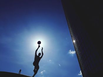 Low angle view of silhouette person against blue sky