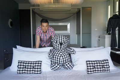 Portrait of man with checked pattern teddy bear on bed at home