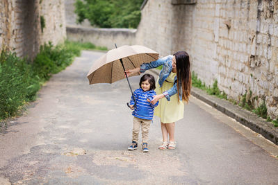 Mother and little eastern handsome baby boy playing with umbrella outdoor