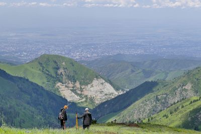 Hikers standing on mountain by landscape