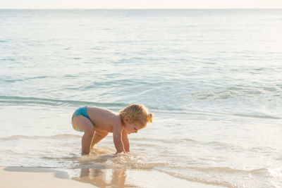 Side view of shirtless boy on shore at beach