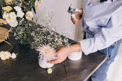 High angle view of a florist making a flower arrangement on a little vase 