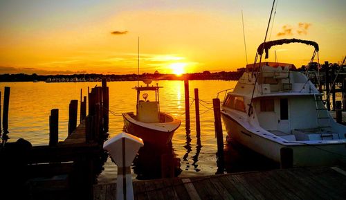 Boats moored at harbor during sunset