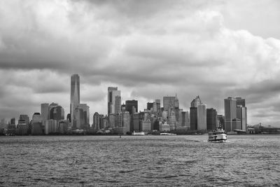 Sea by modern buildings against sky in city