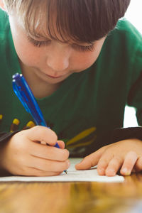 Close-up of boy writing in book