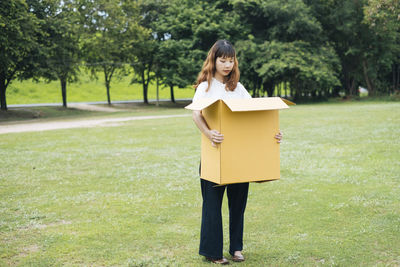 Woman standing on field against trees