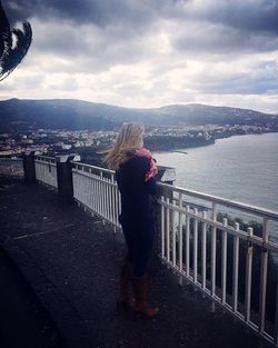 Woman by railing against sky