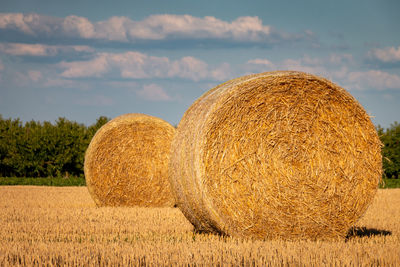 Hay bales on field against sky