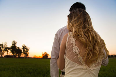Rear view of woman standing against sky during sunset