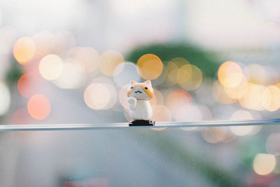 Close-up of figurine on window against defocused lights